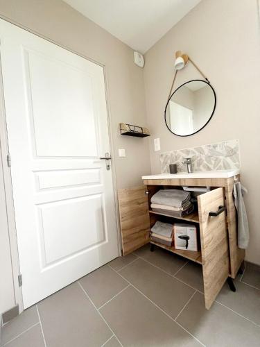 La salle de bains est pourvue d'un lavabo, d'un miroir et d'une porte. dans l'établissement Le Neptune, à Sainte-Mère-Église