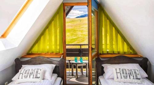 two beds in a room with a window at Willa Czajka - Widokowe Apartamenty in Zakopane