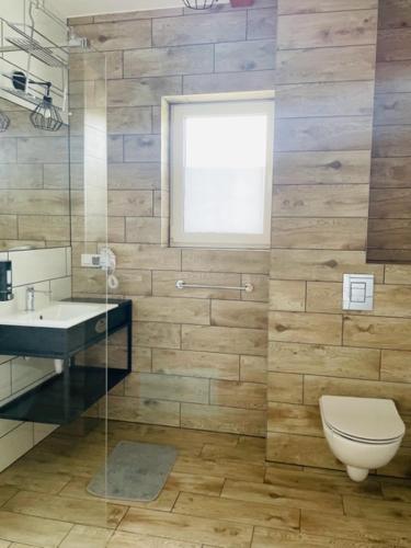 a bathroom with a toilet and a sink and a window at URychertow in Kiełpino