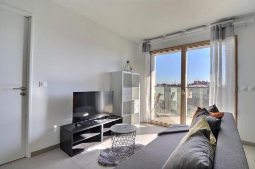 un salon avec un canapé et une grande fenêtre dans l'établissement Lafayette - Part-Dieu District Apartment - Lyon 3rd, à Lyon