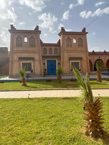 a building with a palm tree in front of it at Kasbah des merveilles Dades in El Hart