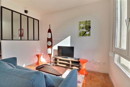 un salon avec un canapé bleu et une télévision dans l'établissement La Douce Parenthèse - Studio with garage - Lyon 4th, à Lyon