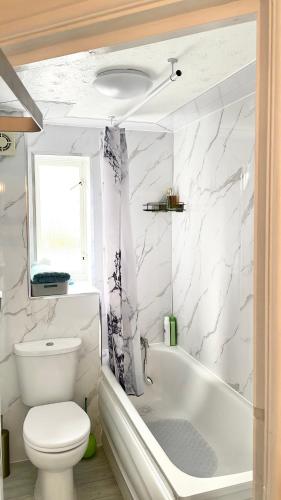 a bathroom with a toilet and a tub and a sink at Juniper Apartment - 2 Bedroom in Goodmayes