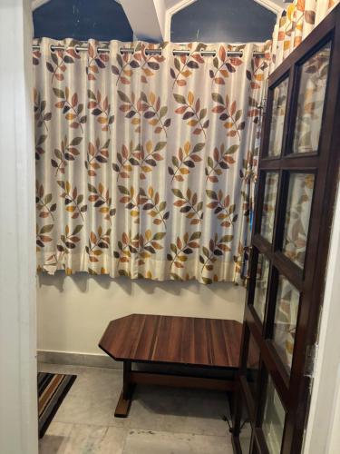 a room with a curtain and a wooden table at Om Sai Villa Guesthouse in Kolkata