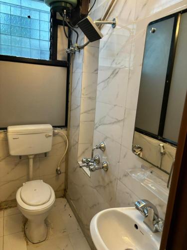 a bathroom with a toilet and a sink and a mirror at Om Sai Villa Guesthouse in Kolkata