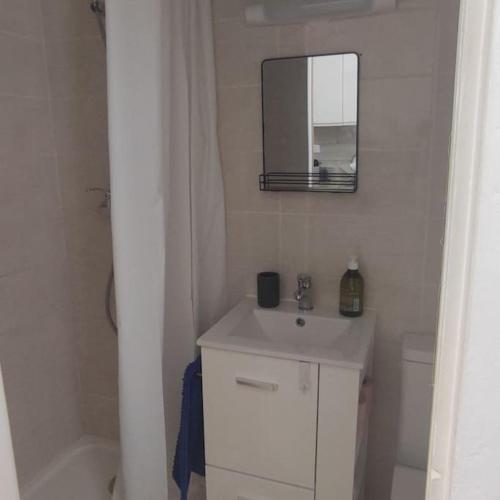 une salle de bain blanche avec un lavabo et un miroir dans l'établissement Logement Climatisé au cœur quartier de Jonquière, à Martigues