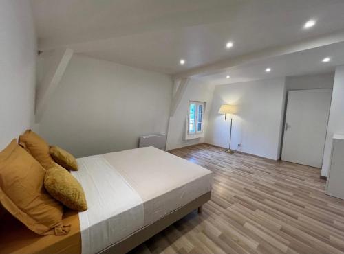 a bedroom with a large white bed and a wooden floor at Le Hameau Arribas in Condé-Sainte-Libiaire