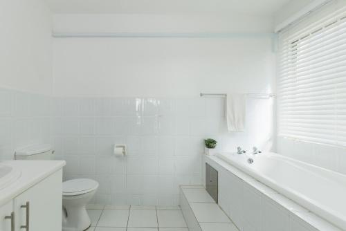a white bathroom with a tub and a toilet at Laguna La Crete 88 in Uvongo Beach