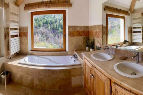 La salle de bains est pourvue de 2 lavabos et d'une baignoire avec une fenêtre. dans l'établissement Mas d'exception en pierre avec piscine et vue, à La Roche-sur-le-Buis