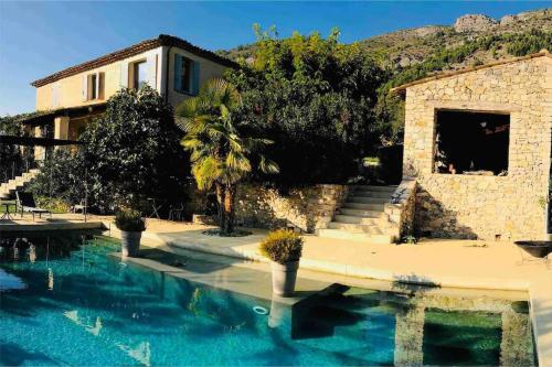 une maison avec une piscine à côté d'un bâtiment dans l'établissement Mas d'exception en pierre avec piscine et vue, à La Roche-sur-le-Buis