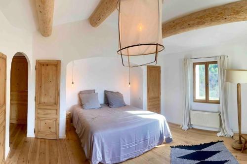 une chambre avec un lit et un lustre dans l'établissement Mas d'exception en pierre avec piscine et vue, à La Roche-sur-le-Buis