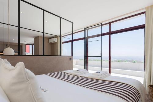 a bedroom with a large bed and large windows at Liiiving in Gaia - Panoramic Terrace Penthouse in Vila Nova de Gaia
