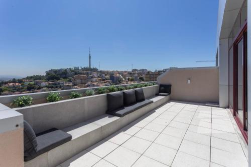 a balcony with couches and a view of a city at Liiiving in Gaia - Panoramic Terrace Penthouse in Vila Nova de Gaia