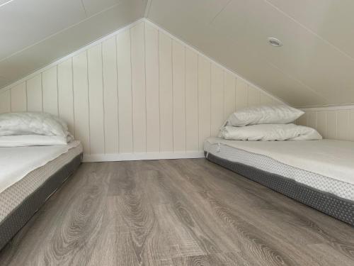 two beds in a room with white walls and wooden floors at Cabin in the forest with Spa bath in Västra Torup