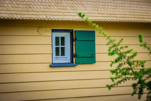 a window on a yellow house with a green shutter at Sonnenhäusle - Natur. Fernblick. Panorama-Sauna. in Sasbachwalden