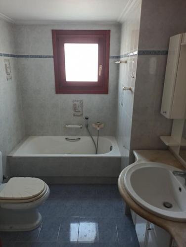 a bathroom with a tub and a toilet and a sink at Nea Peramos Apartment-1 in Nea Peramos
