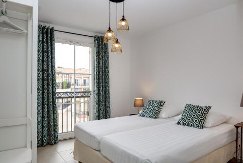 une chambre blanche avec un lit et une fenêtre dans l'établissement Central Elegance Roquefort-les-Pins, à Roquefort-les-Pins