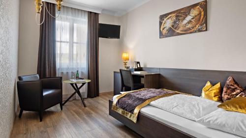 a hotel room with a bed and a chair and a desk at Ambiance Hotel - Braunau - Simbach in Braunau am Inn