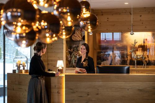 two women standing at a counter in a restaurant at Ciampedie Luxury Alpine Spa Hotel in Vigo di Fassa