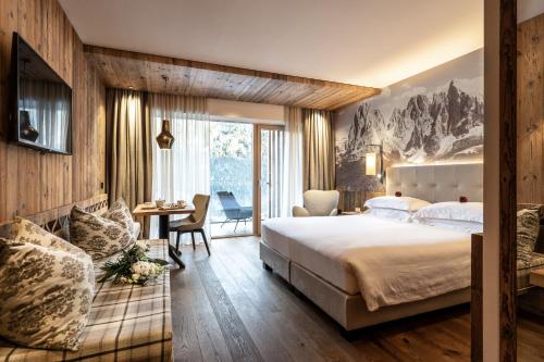 a hotel room with a large bed and a desk at Ciampedie Luxury Alpine Spa Hotel in Vigo di Fassa