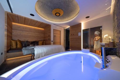 a woman standing in a bathroom with a bath tub at Ciampedie Luxury Alpine Spa Hotel in Vigo di Fassa