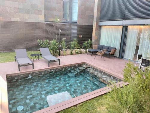 a swimming pool with chairs and a wooden deck at Moradia Prime em Tróia com Piscina Privada in Troia