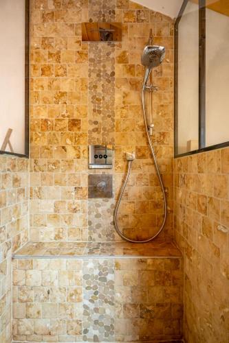La salle de bains est pourvue d'une douche et d'un mur en pierre. dans l'établissement Chalet Neuf 10 personnes, Piscine et Spa, à Bitschwiller-lès-Thann