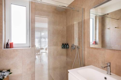 a bathroom with a shower with a sink and a mirror at Regalia Suites - Free Parking in Lugano