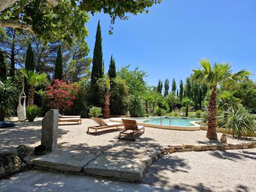 un parc avec deux bancs et une piscine dans l'établissement La maison de Campagne - RENDEZ-VOUS EN PROVENCE, à Monteux