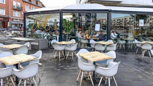 un groupe de tables et de chaises devant un restaurant dans l'établissement Le Doux Refuge, à Calais