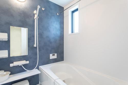 a bathroom with a tub and a sink and a mirror at Mova Villa Ozu in Ozu