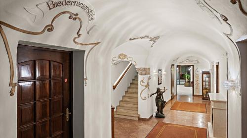a hallway with a door and stairs with a dog standing next to it at Ambiance Hotel - Braunau - Simbach in Braunau am Inn