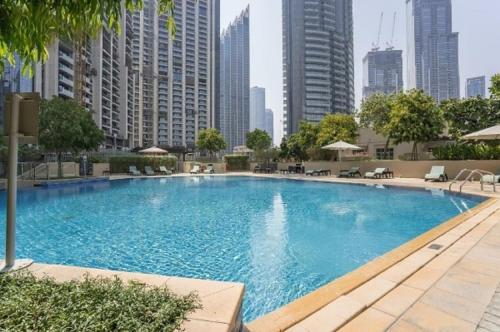 a large swimming pool in a city with tall buildings at Elegant Apartment Overlooking Dubai Mall Fountain. in Dubai
