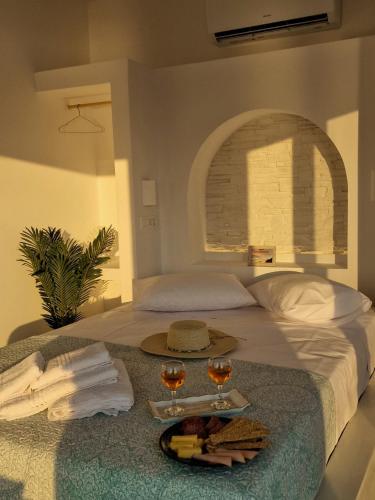 a bed with a tray of food and two glasses of wine at Regina - Luxury Apartments in Kalymnos