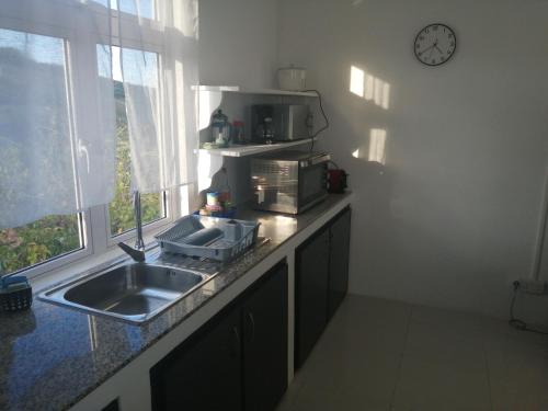 a kitchen with a sink and a clock on the wall at Ô Bercail du Sud chez Jeannette in Rodrigues Island