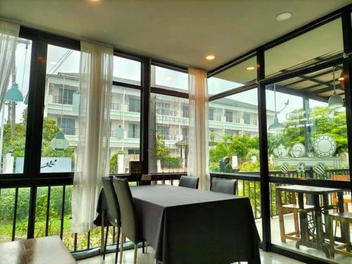 a dining room with a table and chairs and large windows at Privacy Residence Lopburi in Lop Buri