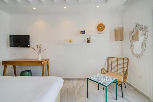 a bedroom with a bed and a chair and a television at San Antonio Summerland in Mýkonos City