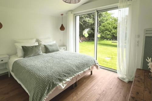 a bedroom with a bed and a large window at Chez Josie, cottage en Bretagne in Bannalec