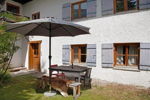 a table with an umbrella in front of a house at Alpenchalet Pfronten in Pfronten