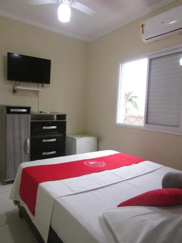 a bedroom with a bed with a red and white blanket at Costa Sol Pousada in Praia Grande