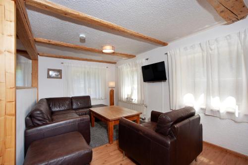 a living room with leather furniture and a television at Alpenchalet Pfronten in Pfronten