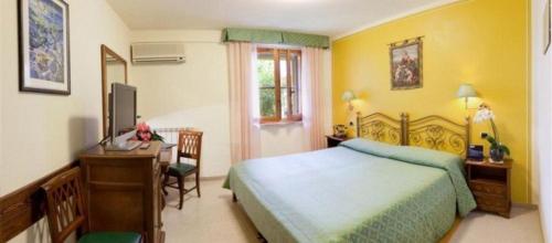 a bedroom with a bed and a desk and a television at Campiglione Hotel in Bastia Umbra