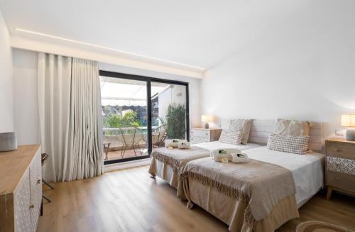 a bedroom with two beds and a large window at Quinta do Lago Luxury Beach Apartment in Almancil