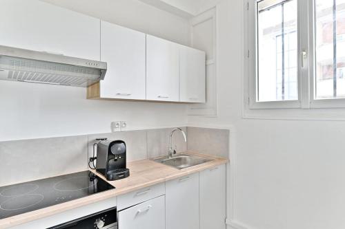 - une cuisine blanche avec un évier et des placards blancs dans l'établissement Studio cosy proche de la capitale - Montreuil, à Montreuil