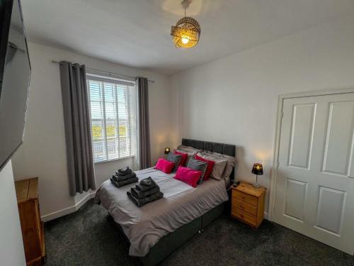 a bedroom with a large bed with pink pillows at North Lodge Retreat Allonby in Maryport