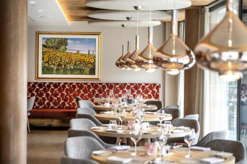 a restaurant with tables and chairs and chandeliers at Ciampedie Luxury Alpine Spa Hotel in Vigo di Fassa