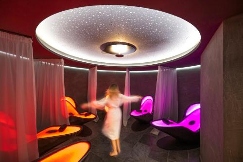 a woman walking through a room with pink chairs at Ciampedie Luxury Alpine Spa Hotel in Vigo di Fassa