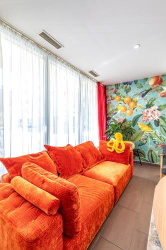 an orange couch in a living room with a large window at A&T Hotel & Hostel in Vienna