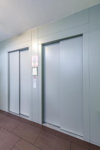 three elevator doors in a building with a sign at A&T Hotel & Hostel in Vienna