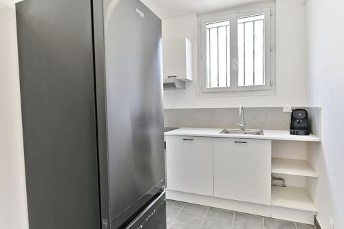 La cuisine blanche est équipée d'un évier et d'un réfrigérateur. dans l'établissement Magnifique studio banlieue Parisienne - Montreuil, à Montreuil